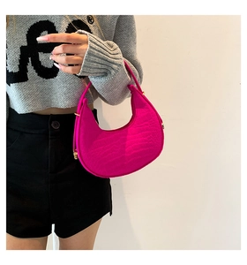 Detailed view of magenta faux crocodile leather underarm bag with gold hardware
