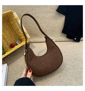 Close-up of dark brown crocodile pattern texture and gold zipper on the crescent bag