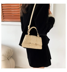Beige woven straw handbag styled as a crossbody on model with black velvet outfit