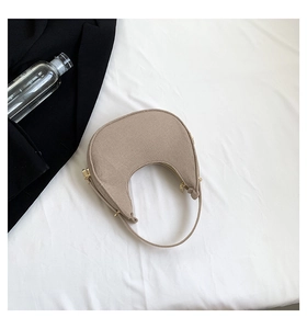 Detail of minimalist beige felt crescent bag with gold metal hardware and fabric strap