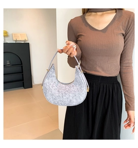 Detail of light grey felt crescent bag with gold metal buckle held by model