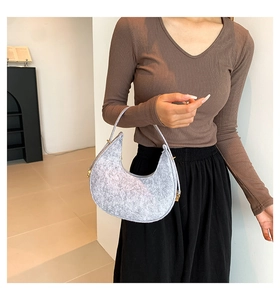 Detail of light grey felt crescent shoulder bag with round handle and gold hardware