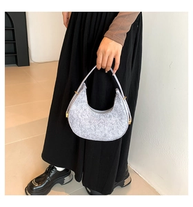 Detail of light gray felt crescent bag with golden metal hardware on the handle