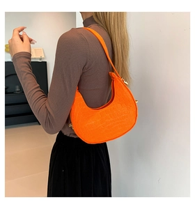 Close-up of bright orange faux crocodile skin texture and zipper on half-moon bag