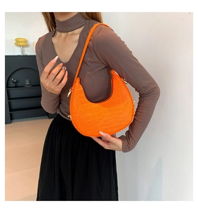 Detail of orange crescent bag with crocodile pattern and golden metal hardware