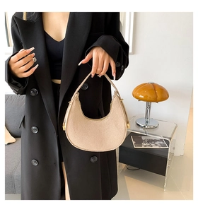 Close-up of beige crescent hobo bag in felt material worn with black blazer