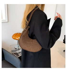 Detail view of dark brown hobo bag with crocodile texture and golden metal buckle
