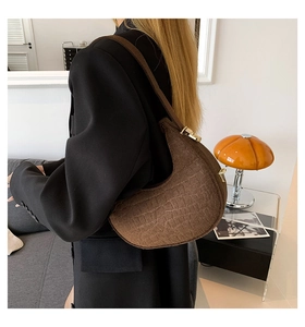 Brown faux crocodile leather half-moon shoulder bag styled on a female model with gold buckle