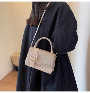 Détail d'un sac à rabat beige avec tissu pailleté et boucle carrée décorative chic