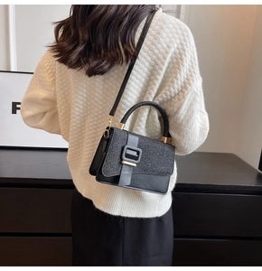 Détail d'un sac bandoulière noir avec rabat pailleté et boucle sur mannequin