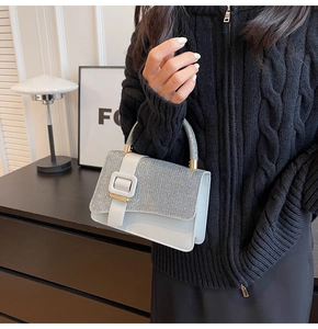 Détail d'un sac bleu clair avec rabat en strass brillants et boucle dorée