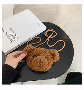 Dettaglio della borsa a tracolla orsetto di peluche su un tavolo con un libro