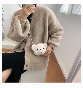 Borsa a tracolla a forma di orso bianco morbido indossata su un cardigan beige