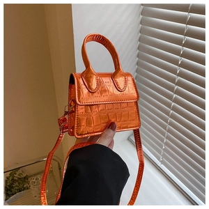 Detailed macro view of orange mini handbag featuring a premium crocodile embossed texture
