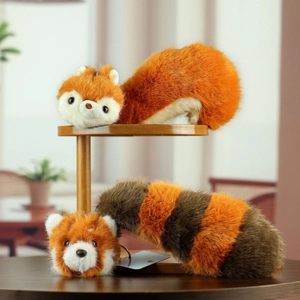 Close-up of soft red panda plush keychains with fluffy tails on a wooden shelf