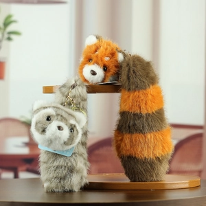 Detail of red panda and raccoon plush keychains with fluffy striped tails and metal rings