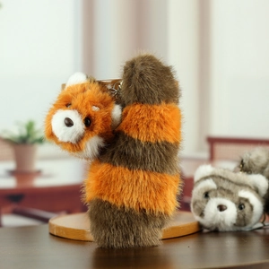Detail shot of a plush red panda keychain with a striped tail and silver metal clasp
