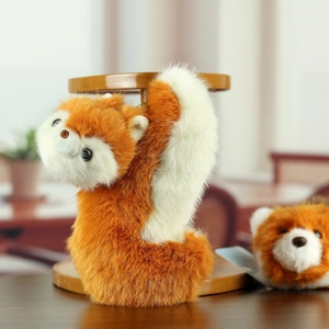 Detailed view of plush red panda keychain with golden ring on a wooden display stand