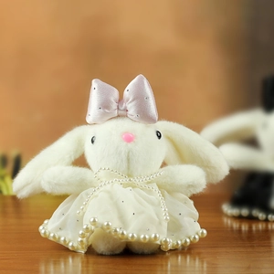 Close-up of white plush bunny with pink satin bow and elegant pearl dress details