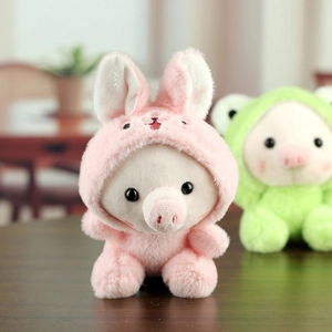 Gros plan d'un porte-clés cochon en peluche portant un sweat à capuche lapin rose
