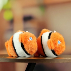 Pair of soft orange clownfish plush keychains with white stripes on wooden background
