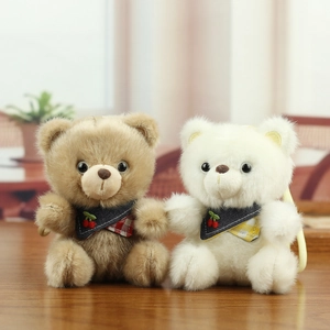 Detailed close-up of fluffy teddy bear plush keychains with cherry bibs on wood