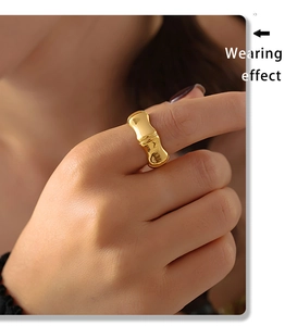Gros plan d'une bague en forme de bambou doré au doigt montrant la texture métallique polie