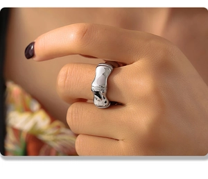 Gros plan détaillé d'une bague large argentée style bambou au doigt d'une femme