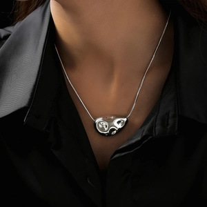 Polished silver liquid lava pendant on a snake chain over a black shirt