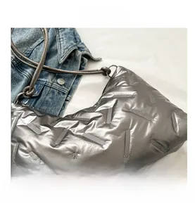 Detailed view of silver quilted puff shoulder bag with textured metallic finish and stitching