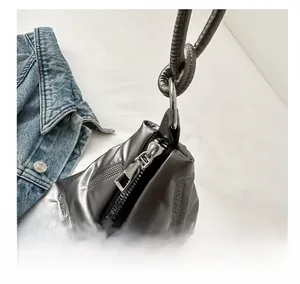 Close-up of metallic silver quilted tote bag featuring a smooth metal zipper detail