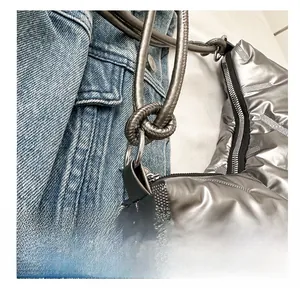 Detail of silver quilted handbag featuring unique knotted handles and zipper closure