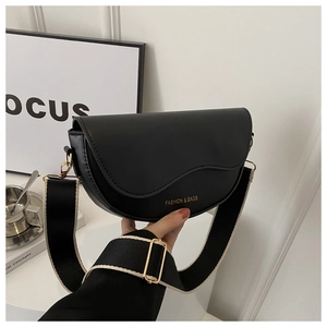 Détail du sac selle noir avec bandoulière rayée et boucle en métal doré brillante