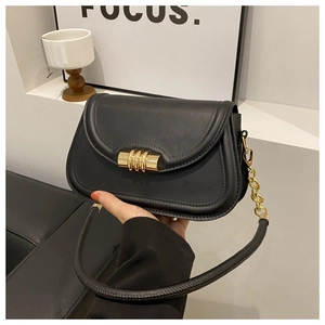 Détail du sac bandoulière en cuir noir avec fermoir doré en spirale et chaîne dorée