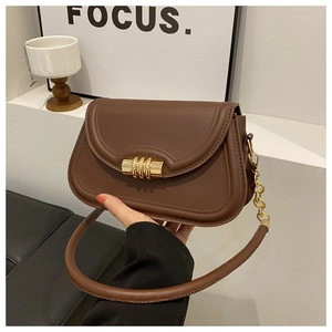 Détail d'un sac selle marron foncé avec fermoir à trois anneaux dorés et chaîne