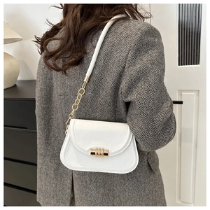 White minimalist crossbody bag with gold metal clasp on a stylish model with blazer