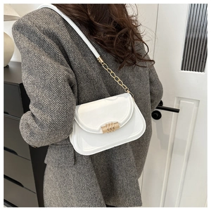 Détail du sac selle en cuir blanc avec boucle dorée et bandoulière en chaîne