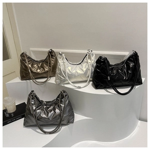Close-up of quilted glossy tote bags in brown, white, black, and grey on a white display