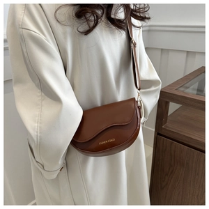Détail d'un sac besace marron avec logo doré et large bandoulière en cuir synthétique