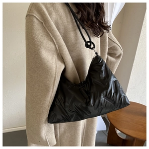 Chic black quilted tote bag with puffer texture and knotted shoulder strap detail on model