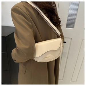 Détail d'un sac besace crème avec texte doré et bandoulière large en sangle tissée