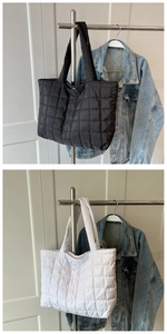 Detail of quilted puffer tote bag in black and white colors with soft padded handles