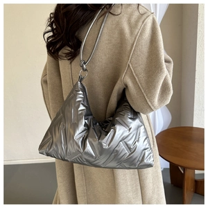 Detail of silver quilted puffer hobo bag featuring a knotted strap and metallic texture