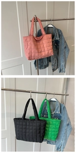 Close-up of three quilted tote bags in pink, black, and green hanging on a wall