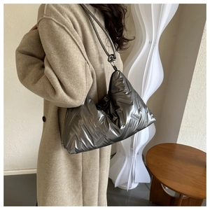 Detail of metallic grey quilted hobo bag with unique knotted shoulder strap and glossy finish