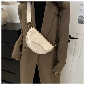 Détail du sac selle crème avec large bandoulière en tissu et finitions dorées