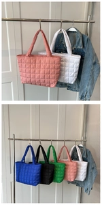 Detailed macro view of quilted nylon tote bags in pink white blue black and green colors
