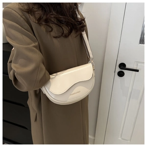 Détail d'un sac besace crème avec bandoulière large et inscription mode élégante