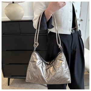 Detail view of metallic silver quilted shoulder bag with knotted rope handle and texture