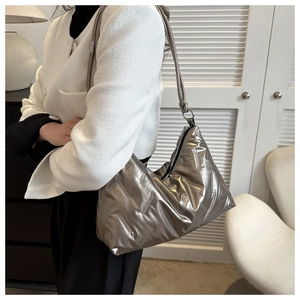 Detailed view of silver quilted puffer shoulder bag featuring a sleek zipper and leather strap